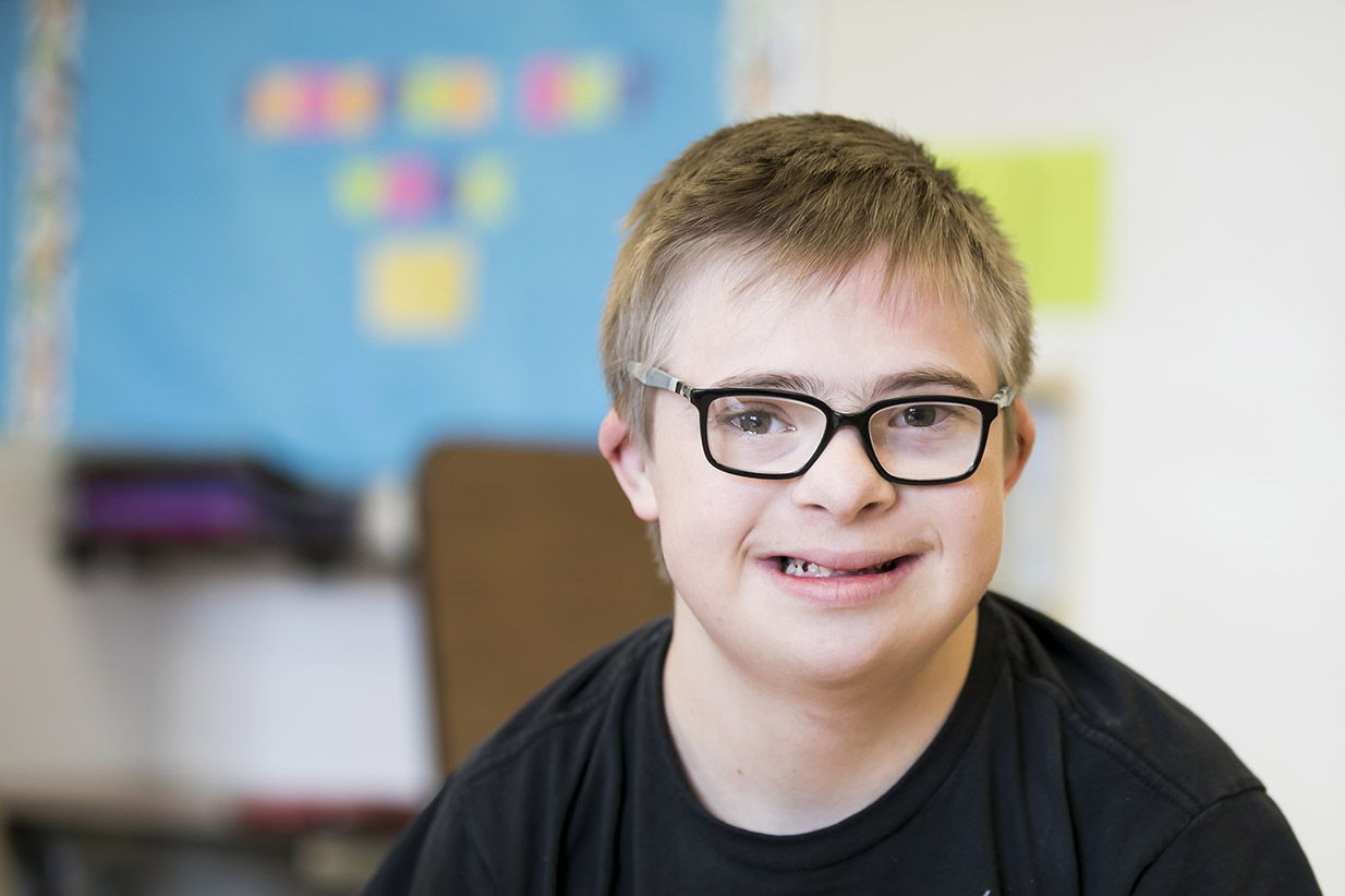 A young, Down Syndrome student smiling.