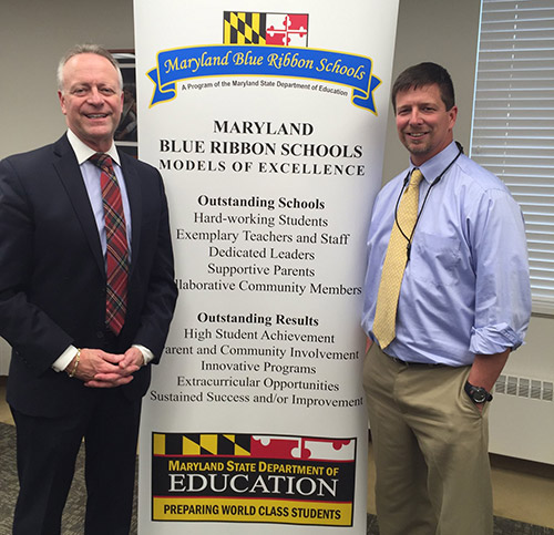 Dr. Martirano standing with Principal Sean Williams in front of banner. Main banner heading reads Maryland Blue Ribbon Schools Models of Excellence